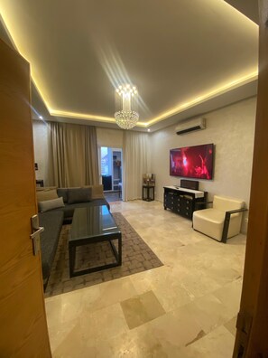 Una sala de estar moderna con un sofá, una mesa de centro y un televisor montado en la pared.