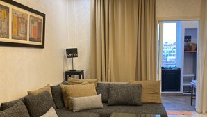 Un salon moderne avec un canapé d’angle, une table basse en verre et un lustre.