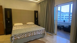 Une chambre moderne avec un grand lit, un tapis rond et une vue sur l’extérieur grâce à une porte-fenêtre coulissante.