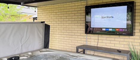 Ein Wellnessbereich mit Whirlpool, einem an einer Ziegelwand montierten Fernseher und einer Decke mit Lichterketten.
