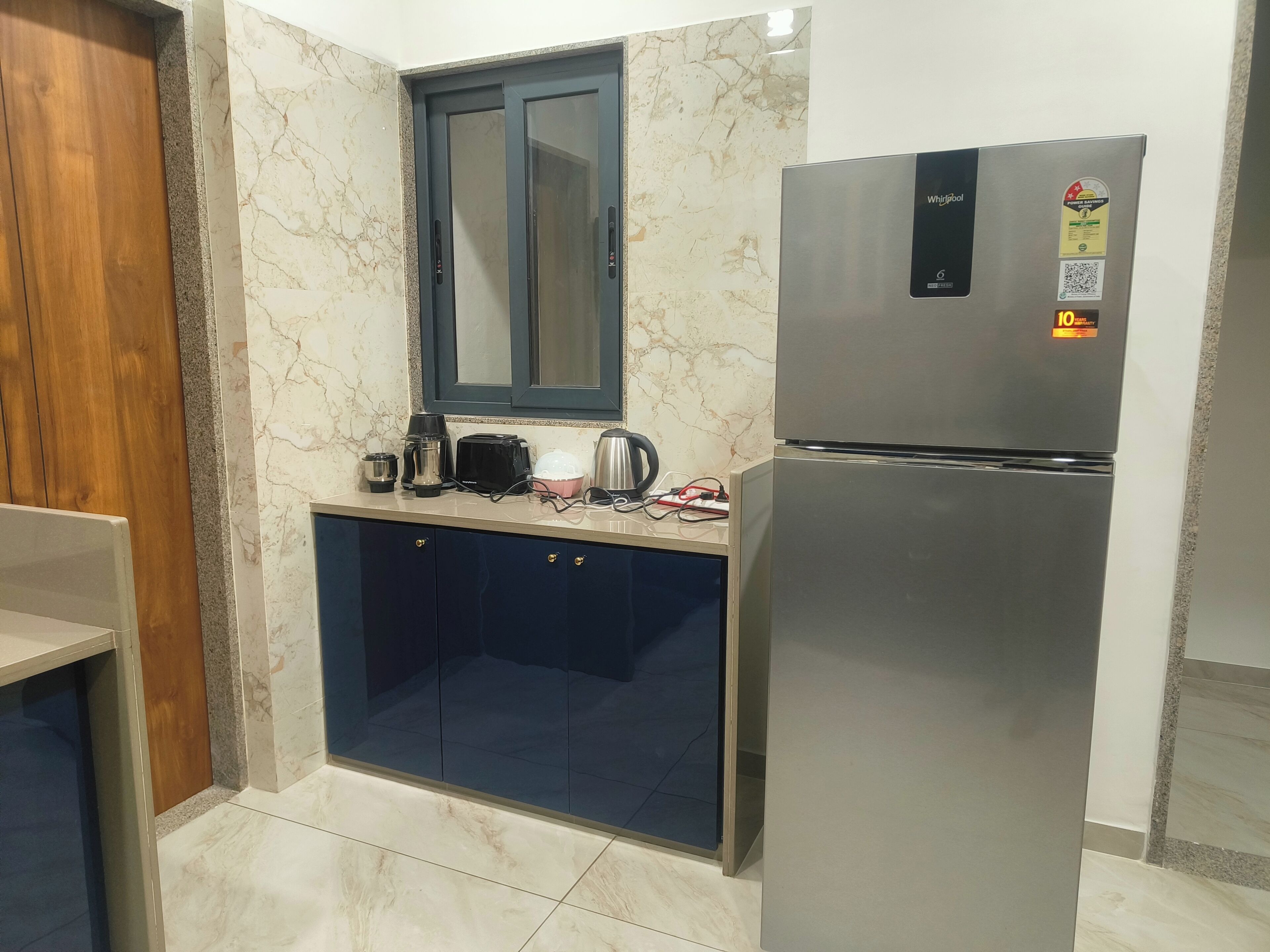A modern kitchen with a stainless steel refrigerator, a built-in oven, and a countertop with a coffee maker, toaster, and kettle.