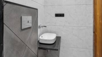 Une salle de bain moderne avec des toilettes blanches, un meuble-lavabo avec un miroir et un espace douche.