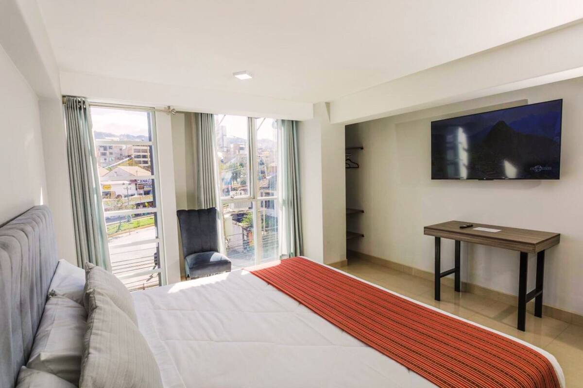 Una camera d'albergo con un letto grande, una TV a muro, una scrivania e una sedia.