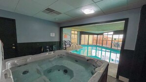 Un espace avec un jacuzzi et une piscine visible à travers les portes vitrées.