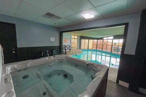 Ein Bereich mit Whirlpool, durch Glastüren ist ein Pool zu sehen.