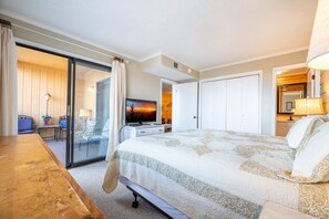 Ein Hotelzimmer mit einem großen Bett, einem Schreibtisch, einem Stuhl, einem Fernseher und einer Glasürband, die zu einem Balkon führt.