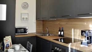 A modern kitchen with dark cabinets, a wooden countertop, a microwave, a sink, and a coffee machine. - Elena House - Mareri apartments (Villa Faraldi)