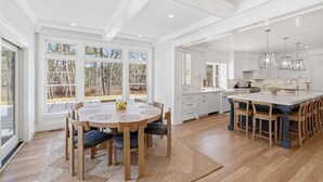 A spacious kitchen with a large island, white cabinetry, and a view of the outdoors. - Olivia's Oasis: 006-HL - Stunning New Construction with Heated Pool & Hot Tub in Harwich (Harwich)