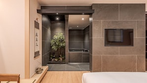 Un bagno moderno con doccia, una piccola pianta e una panca in legno.