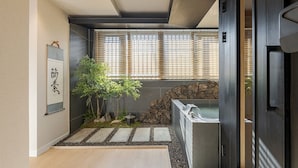 Un bagno moderno con parete in pietra, un piccolo giardino con piante, un vialetto in pietra e una vasca da bagno.
