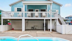 A two-story house with a balcony and a covered garage. - Sea + Second | Pool & Short Walk to the Beach (Ocean Isle Beach)