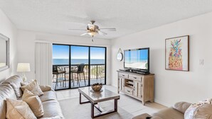 A modern living room with a sofa, coffee table, TV, and artwork. - 403 Sandcastle North Beach front (Indian Rocks Beach)