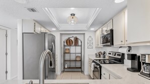 A modern kitchen with a stainless steel refrigerator, a built-in oven, a coffee maker, and a microwave. - 403 Sandcastle North Beach front (Indian Rocks Beach)