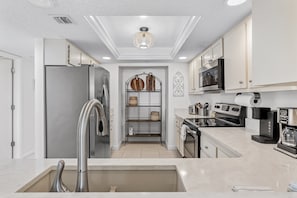 A modern kitchen with a stainless steel refrigerator, a built-in oven, a coffee maker, and a microwave. - 403 Sandcastle North Beach front (Indian Rocks Beach)
