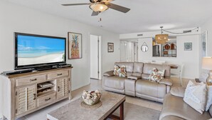 A living room with a television, a ceiling fan, a beige sofa, and a coffee table. - 403 Sandcastle North Beach front (Indian Rocks Beach)