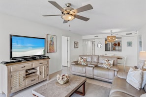 A living room with a television, a ceiling fan, a beige sofa, and a coffee table. - 403 Sandcastle North Beach front (Indian Rocks Beach)