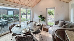 Een eetgedeelte met een ronde tafel, stoelen en een plant.