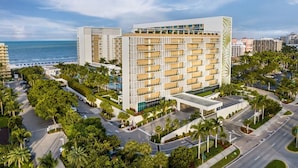Een modern hotel met meerdere verdiepingen, een centrale binnenplaats en uitzicht op de oceaan.