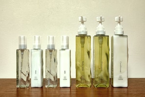 Six Iugen brand bottles of various personal care products on a wooden surface against a plain wall. - HOTEL&SAUNA WAYPOINT SHINANO-MYOKO (Shinano)