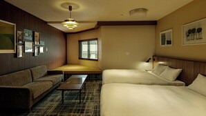 A hotel room with a sofa, a small table, a bed with pillows, a ceiling fan, and framed pictures on the walls. - HOTEL&SAUNA WAYPOINT SHINANO-MYOKO (Shinano)