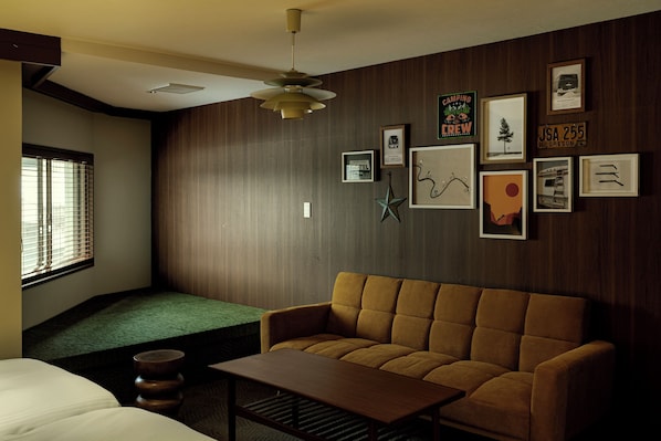 A room with a brown sofa, a wooden coffee table, a green bench, and a window with blinds. - HOTEL&SAUNA WAYPOINT SHINANO-MYOKO (Shinano)
