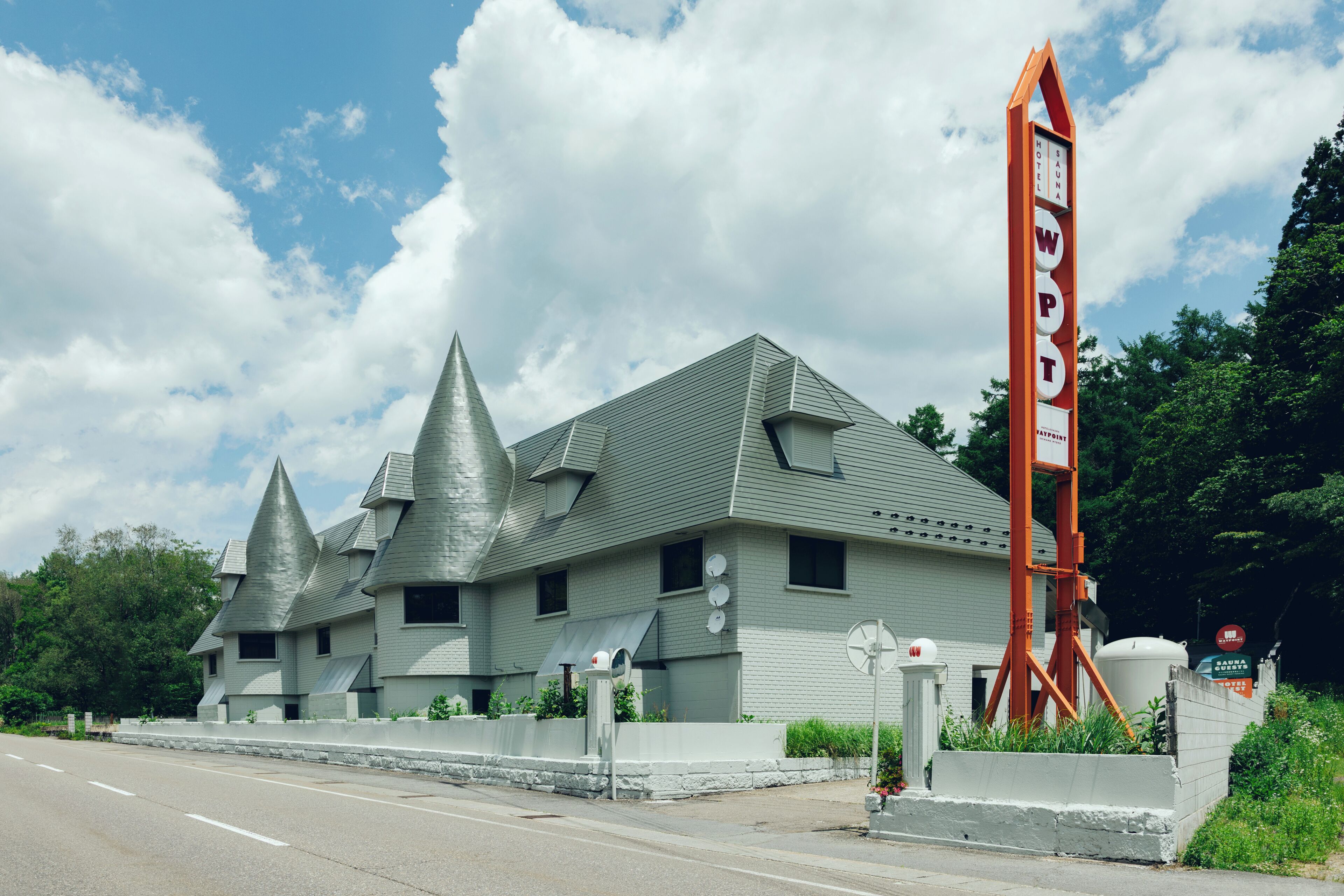 A hotel with a unique architectural design featuring multiple pointed roofs and a prominent orange sign.
