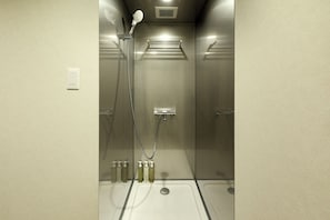 A shower stall with a handheld showerhead, a wall-mounted towel rack, and a set of toiletries on the floor. - HOTEL&SAUNA WAYPOINT SHINANO-MYOKO (Shinano)