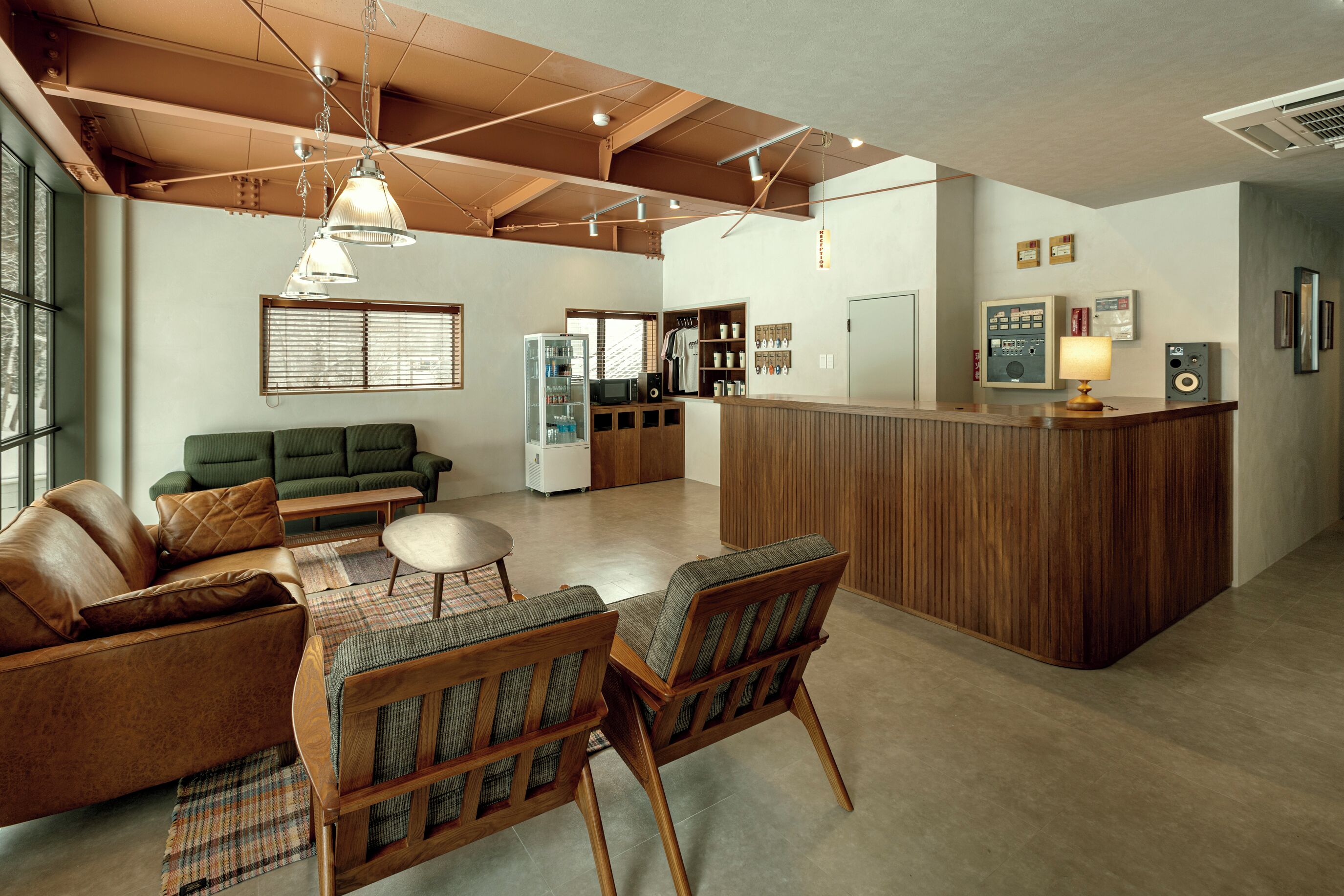 A spacious living area with a wooden ceiling, a green sofa, a brown leather couch, and a wooden dining table with chairs.