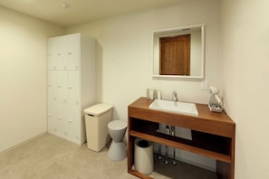 A bathroom with a white sink, wooden vanity, a mirror, a toilet, a trash can, and a storage cabinet. - HOTEL&SAUNA WAYPOINT SHINANO-MYOKO (Shinano)