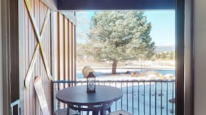A balcony with a round table and a lantern, overlooking a snowy landscape with trees and a distant mountain range. - Ground floor | 1min to Shuttle | Master ensuite | Snowfire 101A 2 (Angel Fire)