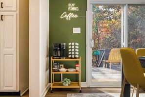 Una cocina con estación de café, un letrero de neón y vistas al exterior.