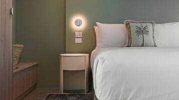 Una camera da letto con un letto, un comodino, una lampada a parete e un piccolo tavolino.