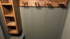 Une salle de bain avec une étagère en bois, un porte-serviettes et un espace douche.