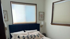Une chambre à coucher avec un grand lit, une tête de lit bleue et une fenêtre avec des stores.