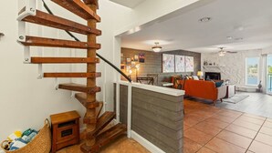 A modern interior with a wooden staircase, a kitchen area, and a living room with a fireplace. - 3BR Water View Condo | Boat Access+Great Location (Treasure Island)
