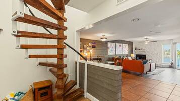 A modern interior with a wooden staircase, a kitchen area, and a living room with a fireplace.
