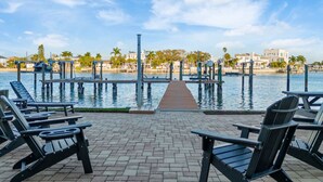 A waterfront patio with lounge chairs and a dock extending into the water. - 3BR Water View Condo | Boat Access+Great Location (Treasure Island)