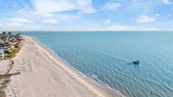 A coastal beach with a clear view of the ocean and a small boat.