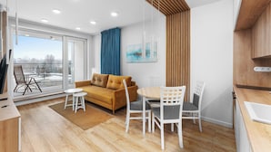 Uma sala de estar moderna com sofá, cadeiras, mesa de jantar e uma janela grande.