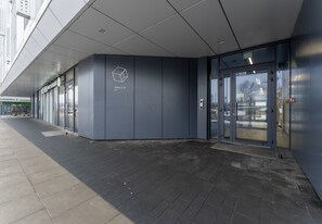 Una entrada moderna con puerta de cristal, un logotipo en la pared y un sendero pavimentado.