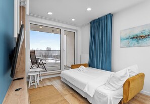 Un hotel moderno con una cama, una pequeña mesa con sillas, un televisor y vistas al exterior.