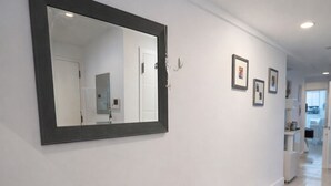 A hallway with a large mirror, a cushioned bench with baskets, and framed pictures on the wall.