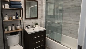 A modern bathroom with a toilet, vanity, and shower.