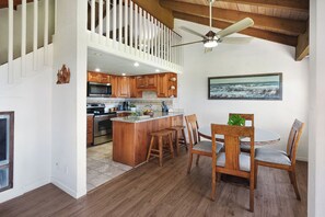 A spacious kitchen with wooden cabinets, a central island, and a dining area with wooden chairs. - Luxury Ocean-View 2BR Condo | Walk to Poipu Beach | Sleeps 6 (Koloa)