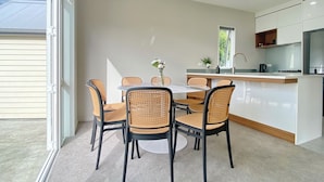Eine moderne Küche mit Essbereich, mit einem runden Tisch und Stühlen, einem Fenster und eingebauten Schränken.