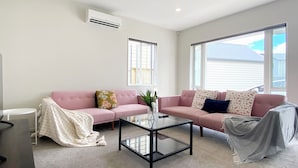 Ein Wohnzimmer mit zwei rosafarbenen Sofas, einem Glastisch und einer weißen TV-Konsole.