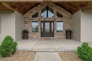 Un bâtiment doté d’une façade en pierre, d’un toit en bois et d’une entrée symétrique agrémentée de deux plantes en pot.