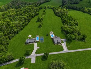 An aerial view of a residential area with two houses, a tennis court, and a swimming pool. - Pool | Sleeps 18 | Hot Tub |Firepit | Playset | (Williamstown)