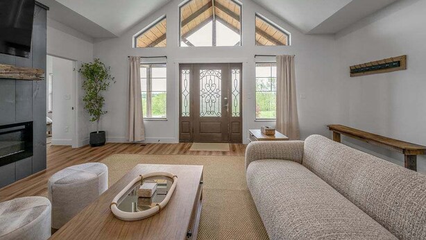 Een moderne woonkamer met een open haard, een bank, een salontafel en een groot raam met uitzicht.