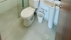 A bathroom with a glass-enclosed shower, a toilet, a sink, and a mirror. - 3-bedroom apartment in enjoyable Barranquilla with AC for relaxing stays (Barranquilla)